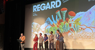 Six artisans de cinéma sur une scène à une remise de prix avec un présentateur
