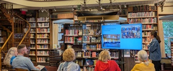 Une personne fait une présentation sur écran à un groupe constitué principalement d'aînés, dans une bibliothèque
