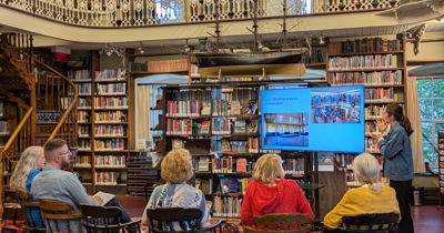 Une personne fait une présentation sur écran à un groupe constitué principalement d'aînés, dans une bibliothèque